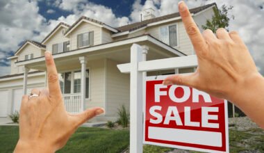 female hands framing home for sale real estate sign in front of new house.